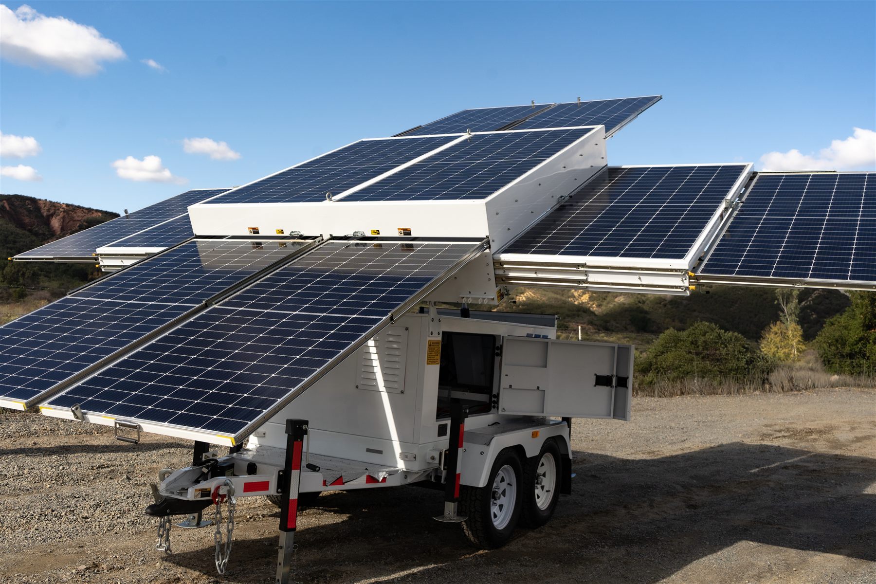 123-SG-4D41 — Ten panels unfolded in the brush: the 4.6 kW array opens around the enclosure of the two-axle trailer.