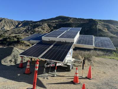 123-SG-4D41 — Array open on a gravel pad below dry hills, the trailer coned off